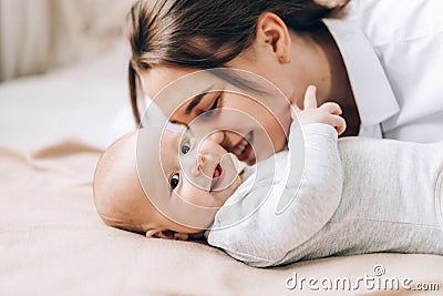 Young mother plays and talks with her newborn baby. Love and care for children. Adoption of children. The child grows up Stock Photo