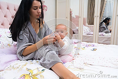 Young mother preparing a bottle feed for her baby. Stock Photo