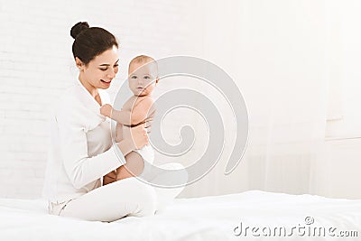 Young mother sitting with baby on bed Stock Photo