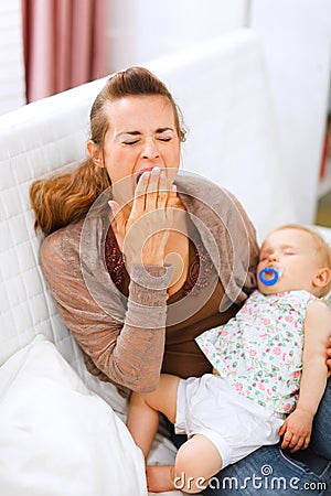 Young mother with sleeping baby on hands yawing Stock Photo