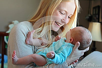 Young Mother Smiling at Newborn Baby in Home Nursery Stock Photo