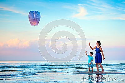 Young mother and son flying fire lantern together Stock Photo