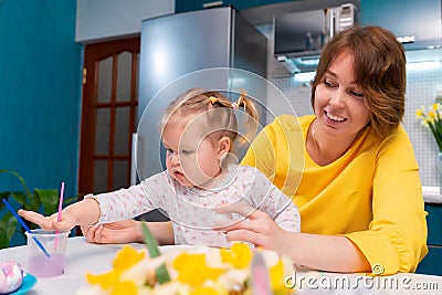 Young mother teaching little daughter are painting Easter eggs. Funny family leisure. Concept of preschool education Stock Photo