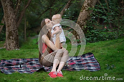 Young mother tenderly hugging her baby on nature background. Togetherness relaxation concept with kid Stock Photo