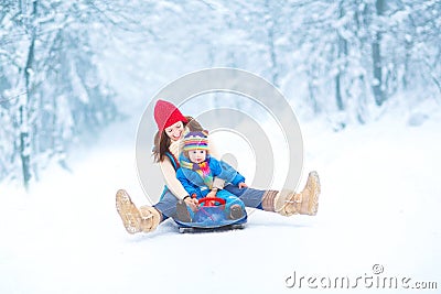 Young mother and toddler daughter enjoying sledge Stock Photo