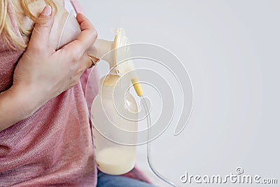 Young mother is using single electric breast milk pump and pumping breast milk for her baby. Breast milk for supplementary feeding Stock Photo