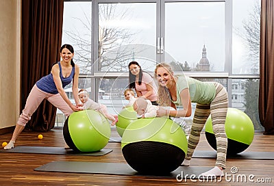 Young mothers and their babies doing yoga exercises on rugs at fitness studio. Stock Photo