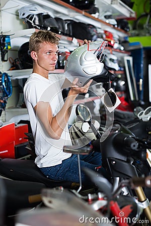 Young motorcyclist choosing new helmet for motorcycle Stock Photo
