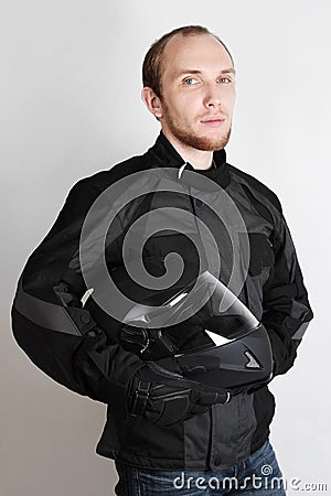 Young motorcyclist man holding helmet in studio Stock Photo