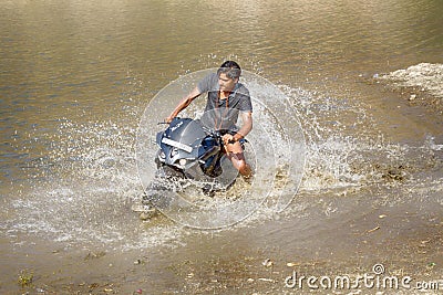 young motorcyclist rushes in the water in a spray at high speed Editorial Stock Photo