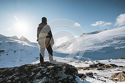 Young mountaineer standing on snowy hill with sunlight shine on winter at Lofoten Islands Stock Photo