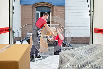 Young Movers Unloading The Boxes In The Van Stock Photo