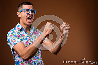 Young multi-ethnic Asian tourist man against brown background Stock Photo