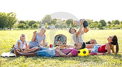 Young multiracial families having fun playing with kids at pic nic garden party - Multiethnic joy and love concept Stock Photo