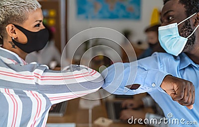 Young multiracial workers wearing face mask doing new social distance greetings bumping elbows inside co-working space Stock Photo