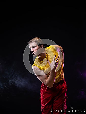 a young muscular man in a bright outfit poses in a pretentious pose, Stock Photo