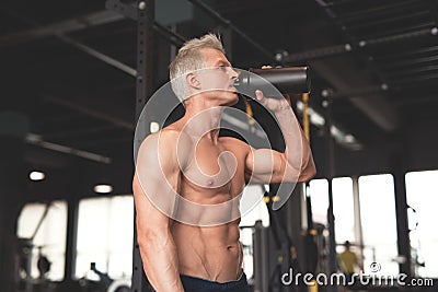 Young muscular man showing his perfect body. Man drinking from a cocktail shaker with the protein. Toned image Stock Photo