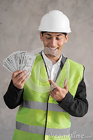 Young muslim builder man engineer wearing safety helmet holding money dollars as payment over background, a foreman Stock Photo