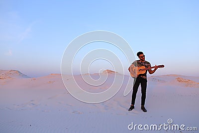 Handsome male Arab playing guitar standing in middle of bottomle Stock Photo