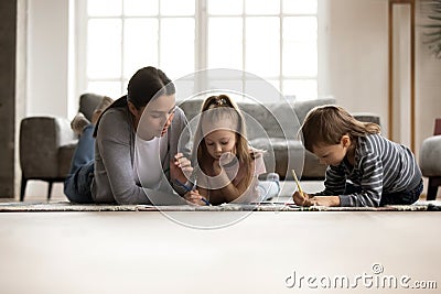 Young nanny babysitter drawing picture with small children. Stock Photo