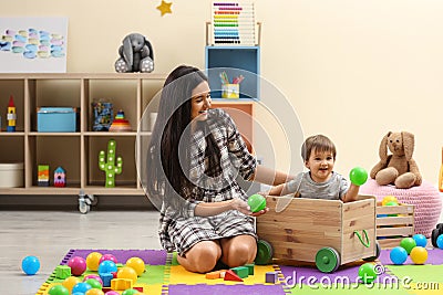 Young nanny and cute little baby playing with toys Stock Photo