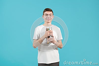 Young nerd guy with glasses naively smiles and holds books in his hands Stock Photo