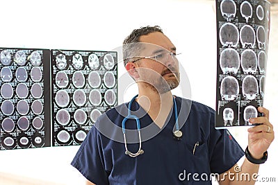 Young neurologist specialist medical doctor in glasses and beard analyzing brain scans on x-rays to find any disease in the patien Stock Photo