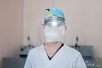 Young neurosurgeon man in glasses with binary loupes for microsurgery with light in the operating room. Modern medicine. Stock Photo