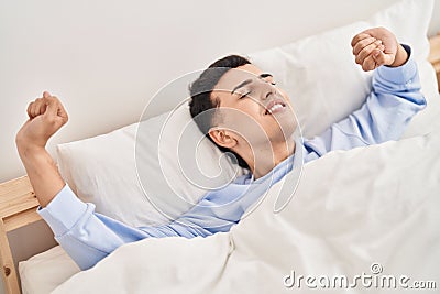 Young non binary man waking up stretching arms Stock Photo