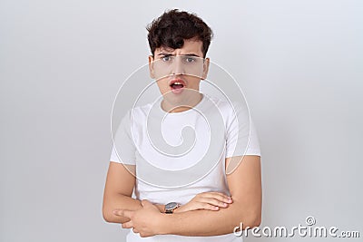 Young non binary man wearing casual white t shirt in shock face, looking skeptical and sarcastic, surprised with open mouth Stock Photo