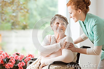 Young nurse helping an elderly woman in a wheelchair. Nursing ho Stock Photo