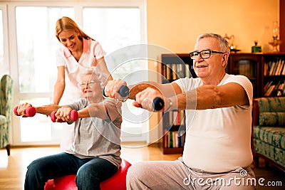 Nurse at nursing home helps senior people to doing exercises Stock Photo