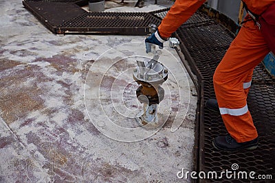 Young offshore engineer sounding fuel oil cargo tank on cargo deck on supply vessel in harbor. Stock Photo