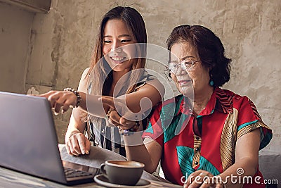 Young and old asian women are using laptop together Stock Photo