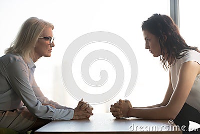 Young and old businesswomen sitting opposite, generations conflict at work Stock Photo