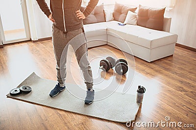 Young ordinary man go in for sport at home. Ordinary freshman in workout stand on mat and hold hands on hips. Cut view Stock Photo