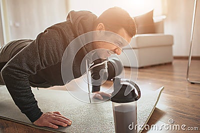 Young ordinary man go in for sport at home. Wink and scream because of hard exercises for freshman or ordinary guy at Stock Photo