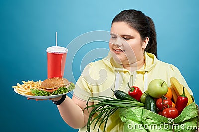 Oversized girl choosing between healthy eating and fast food Stock Photo