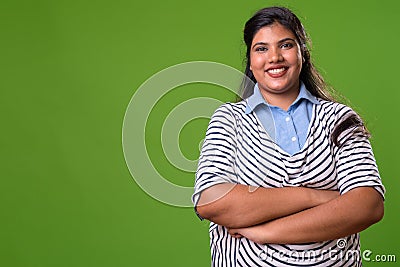 Young overweight beautiful Indian businesswoman against green background Stock Photo
