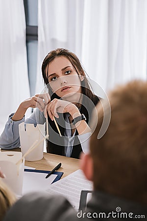 young overworked manageress sitting at workplace with box of chinese food Stock Photo