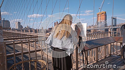 Young painter on Brooklyn Bridge - street art - NEW YORK CITY, USA - APRIL 2, 2017 Editorial Stock Photo