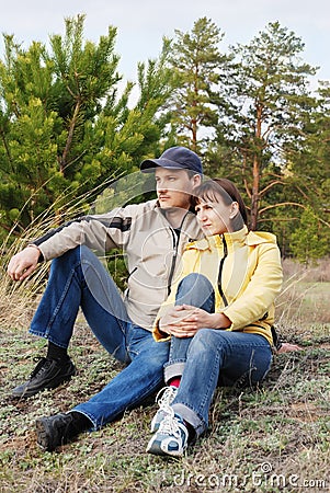 The young pair sits on a hill in a wood Stock Photo