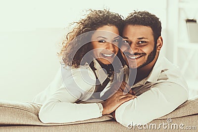 Young Pakistani Couple Sitting on Sofa and Hugging Stock Photo