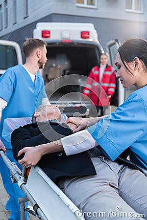 young paramedics moving wounded man Stock Photo