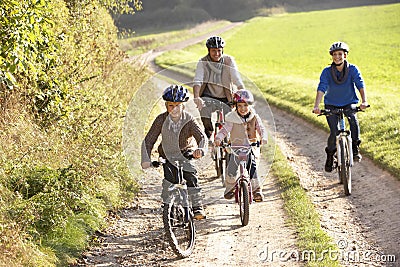 Young parents with children ride bikes in park Stock Photo