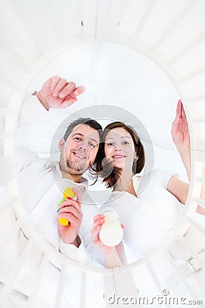 Young parents looking at their baby in a round crib Stock Photo