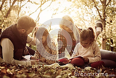 Parents in park with their daughters having education and teaching daughters to writing. Stock Photo