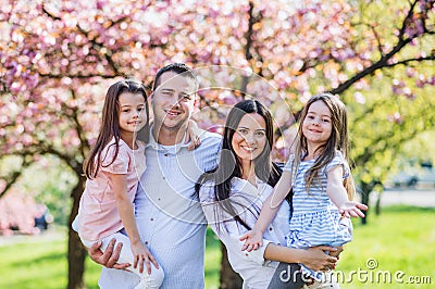 Young parents with small daugthers standing outside in spring nature. Stock Photo
