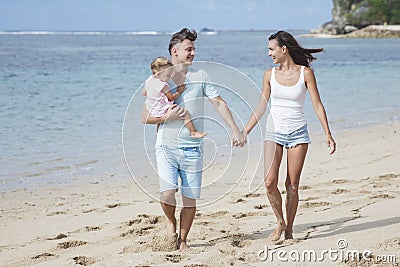 young parents and their cute little daughter walking at the beach Stock Photo