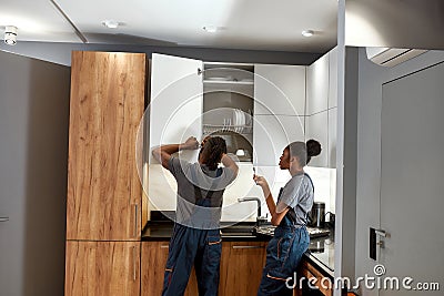 Young passive female apprentice looking at working handyman Stock Photo